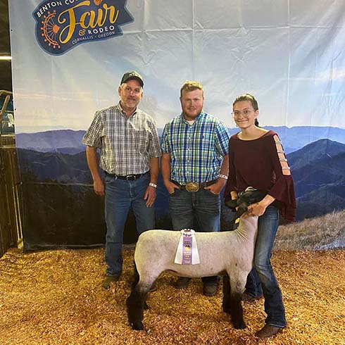 Chloe posing with family and an award ribbon on her sheep after a livestock competition